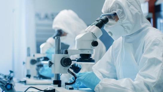 Two researchers with microscope in cleanroom